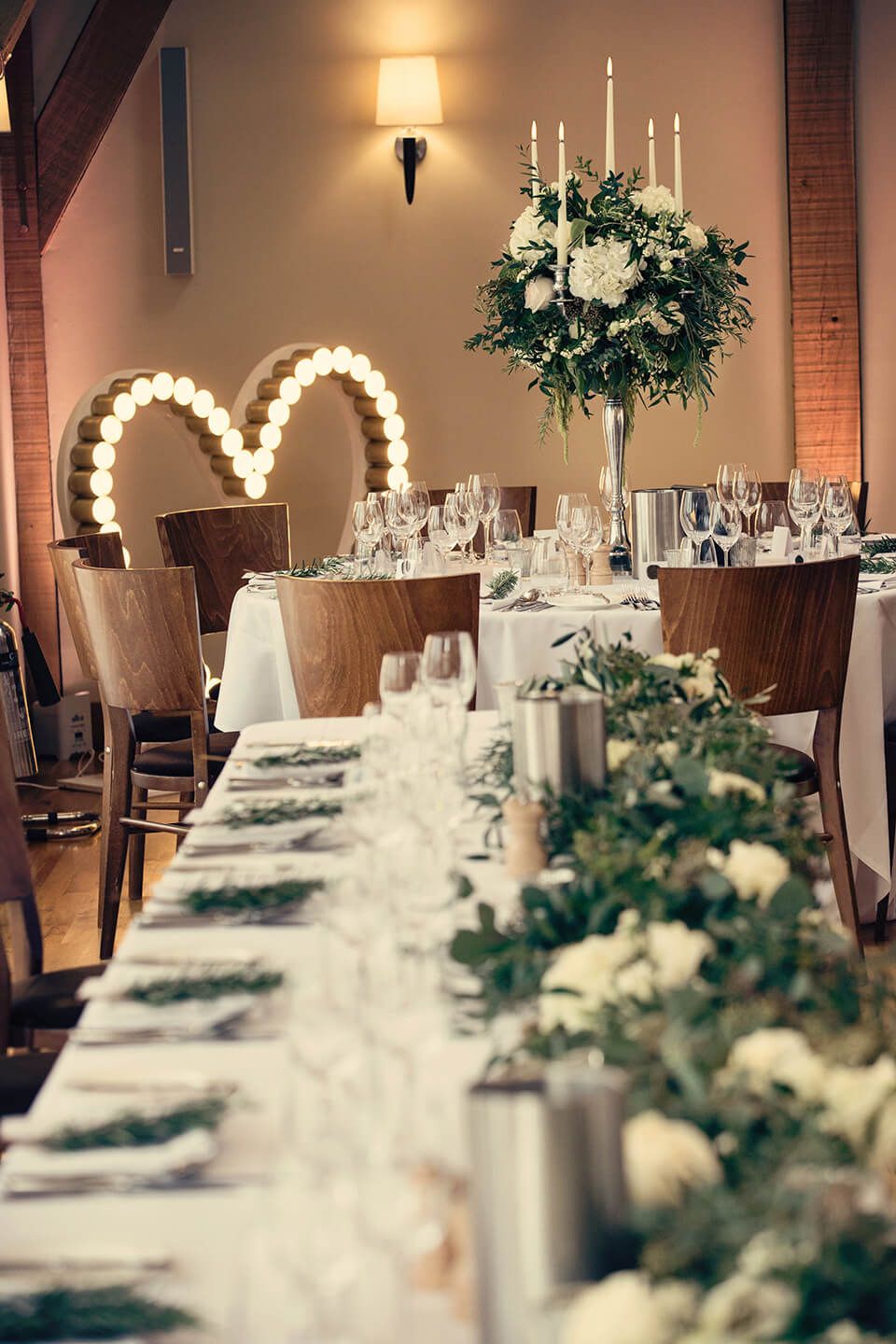 White and green florals adorn tables for an elegant wedding breakfast at Bassmead Manor Barns