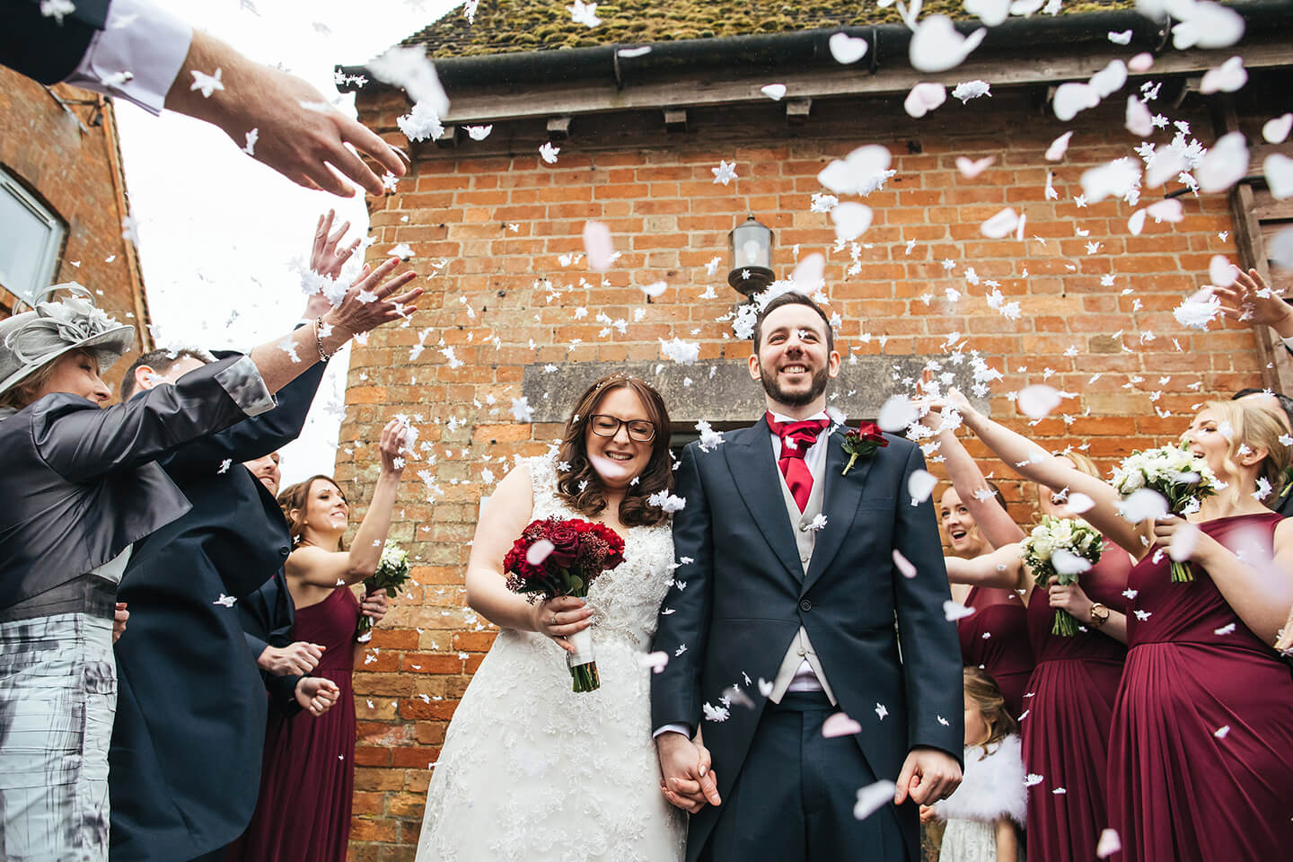 Newlyweds are showered in snowflake confetti after their winter wedding ceremony at Bassmead Manor Barns