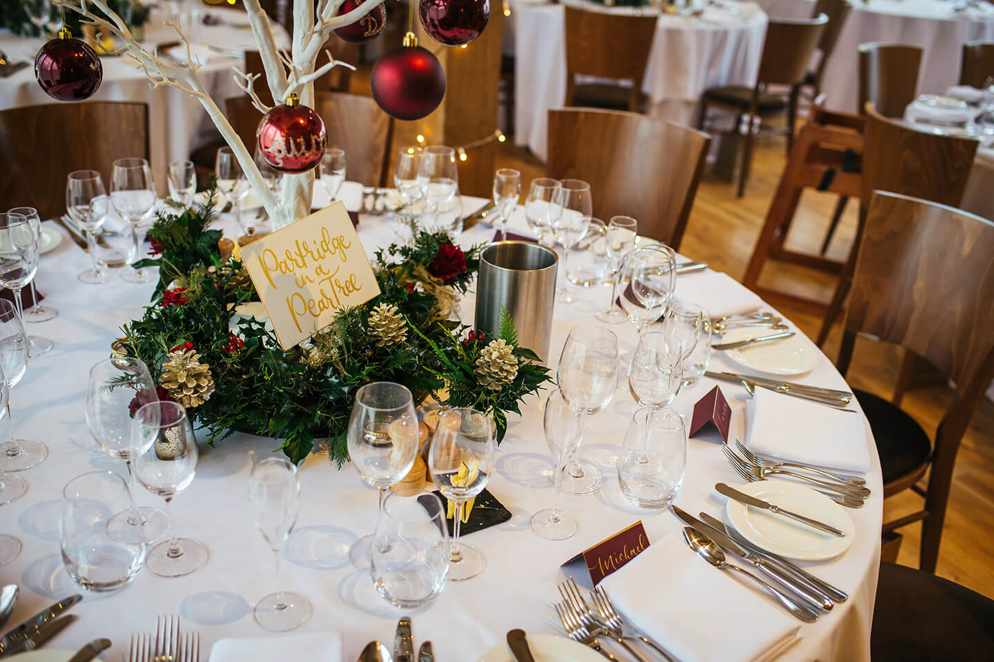 Pine cones and baubles decorate the tables at a winter wedding reception at Bassmead Manor Barns