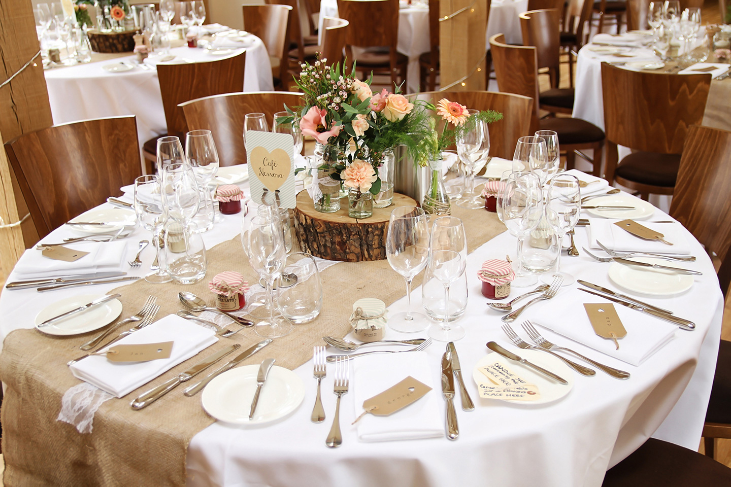 Tables in the Bridge Barn at Bassmead Manor Barns are set up for a rustic wedding breakfast