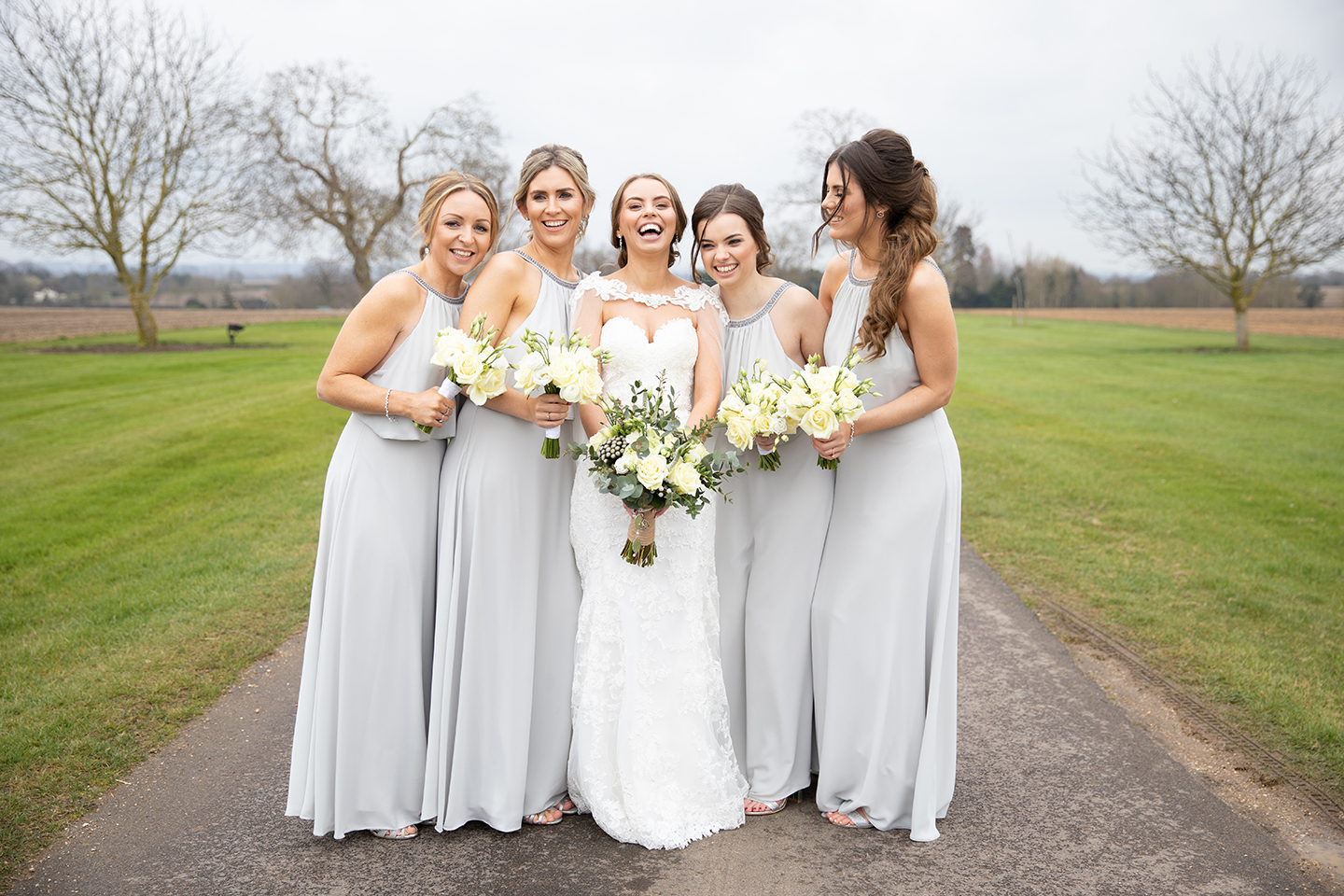The bride enjoys some time at Bassmead Manor Barns with her bridesmaids who wear grey bridesmaids dresses