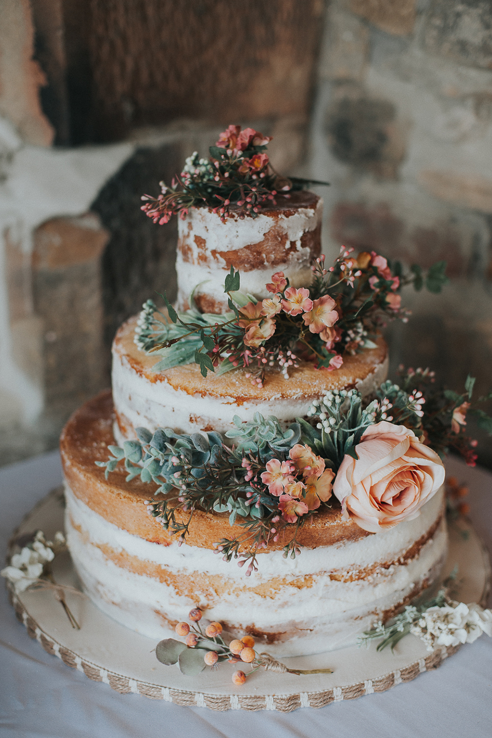 A naked wedding cake decorated with wild florals is the perfect choice for a rustic wedding at Bassmead Manor Barns